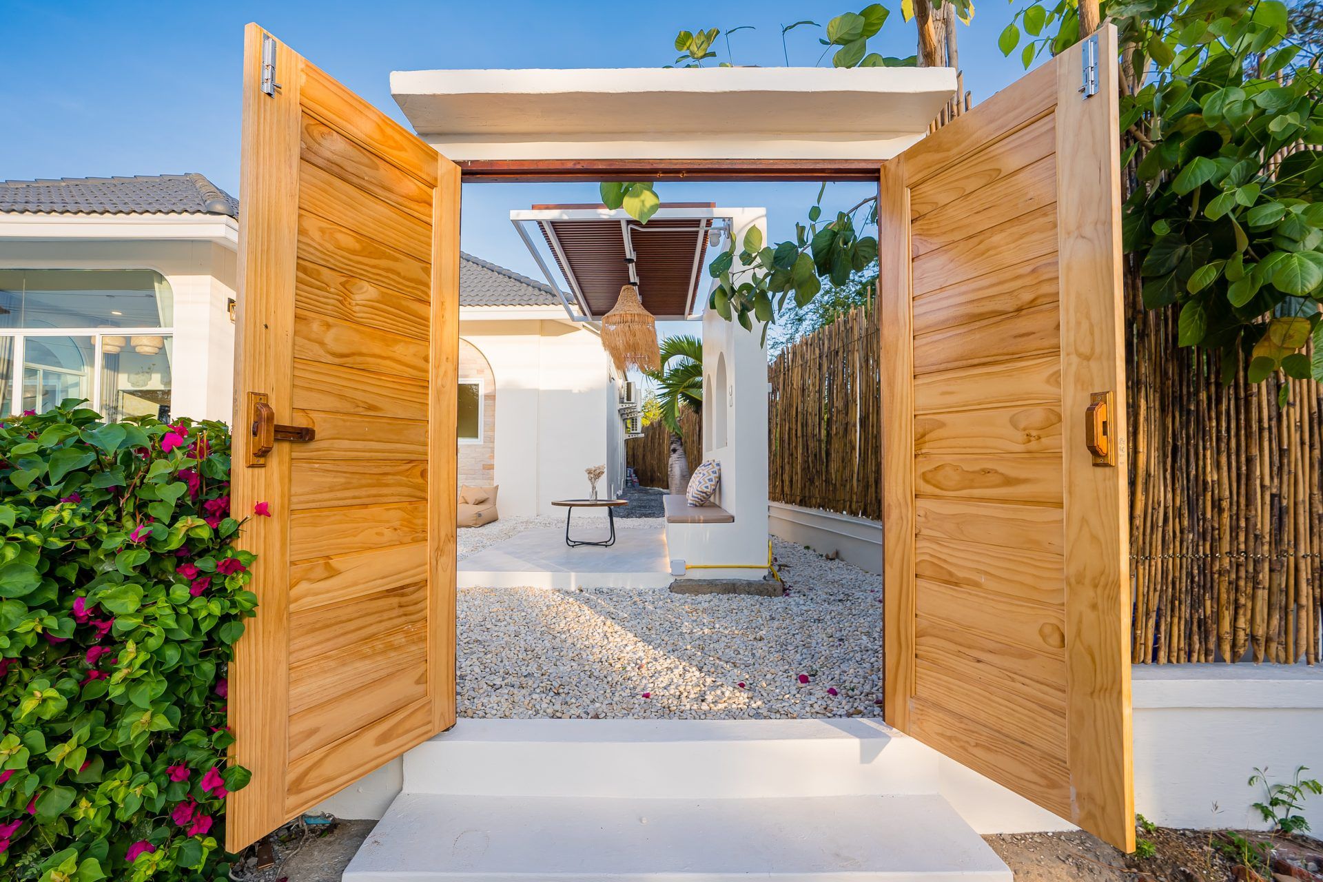 Open wooden gate at Lagoon Beach V Pool Villa, near Bang Kao Beach, Cha-am. View of the courtyard with white gravel.