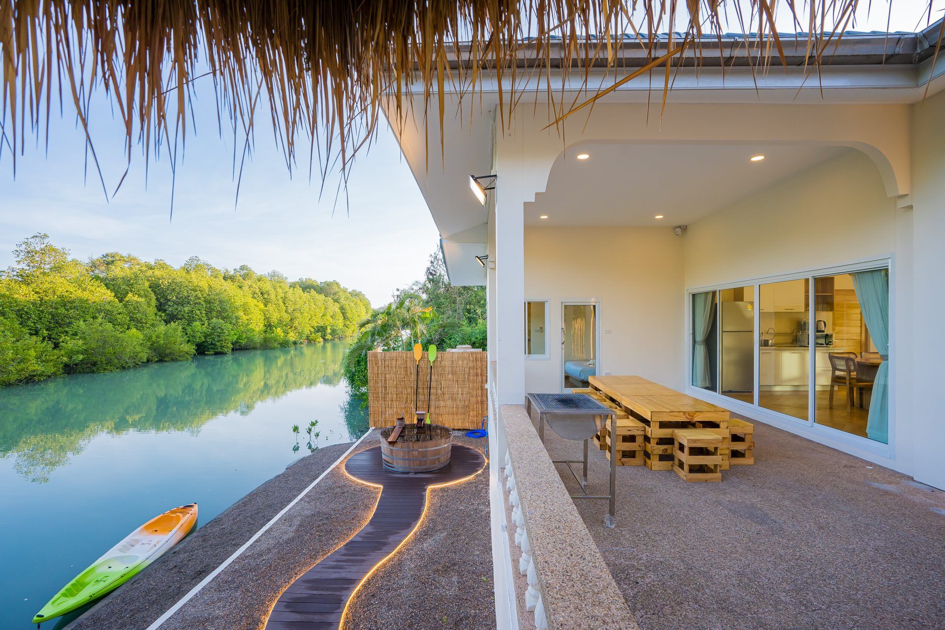 Riverside terrace with BBQ and dining at Lagoon Beach V Pool Villa, ใกล้หาดบางเก่า-ชะอำ. Kayak on the water.