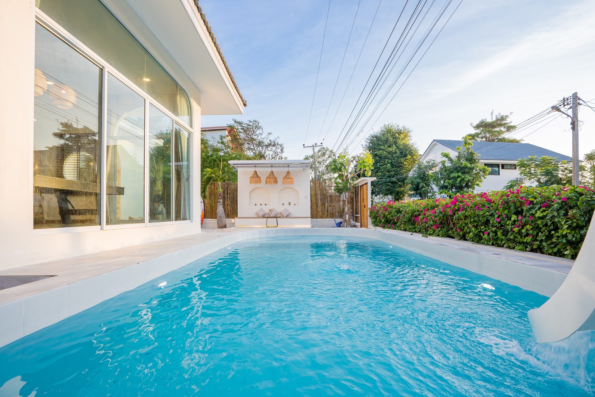 Lagoon Beach V Pool Villa pool with water slide, ใกล้หาดบางเก่า-ชะอำ. Bright blue water and white tile. Outdoor seating area