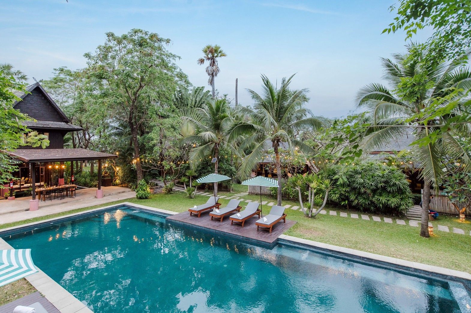 Aerial view of Le Way Pran Pool Villa's turquoise pool and lounge chairs with umbrellas in สามร้อยยอด ปราณบุรี.