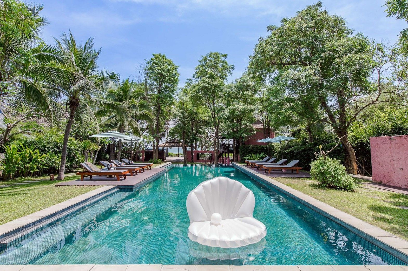 Le Way Pran Pool Villa swimming pool with shell float. Loungers and umbrellas line the pool deck in Sam Roi Yot, Thailand.