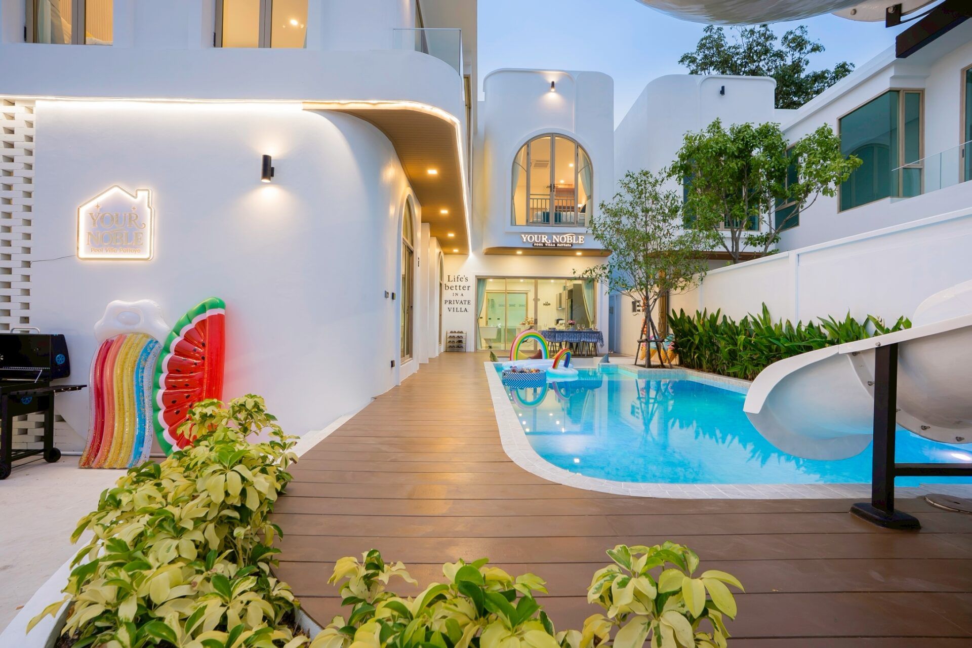 Pool at twilight with slide and rainbow floats at Noble V