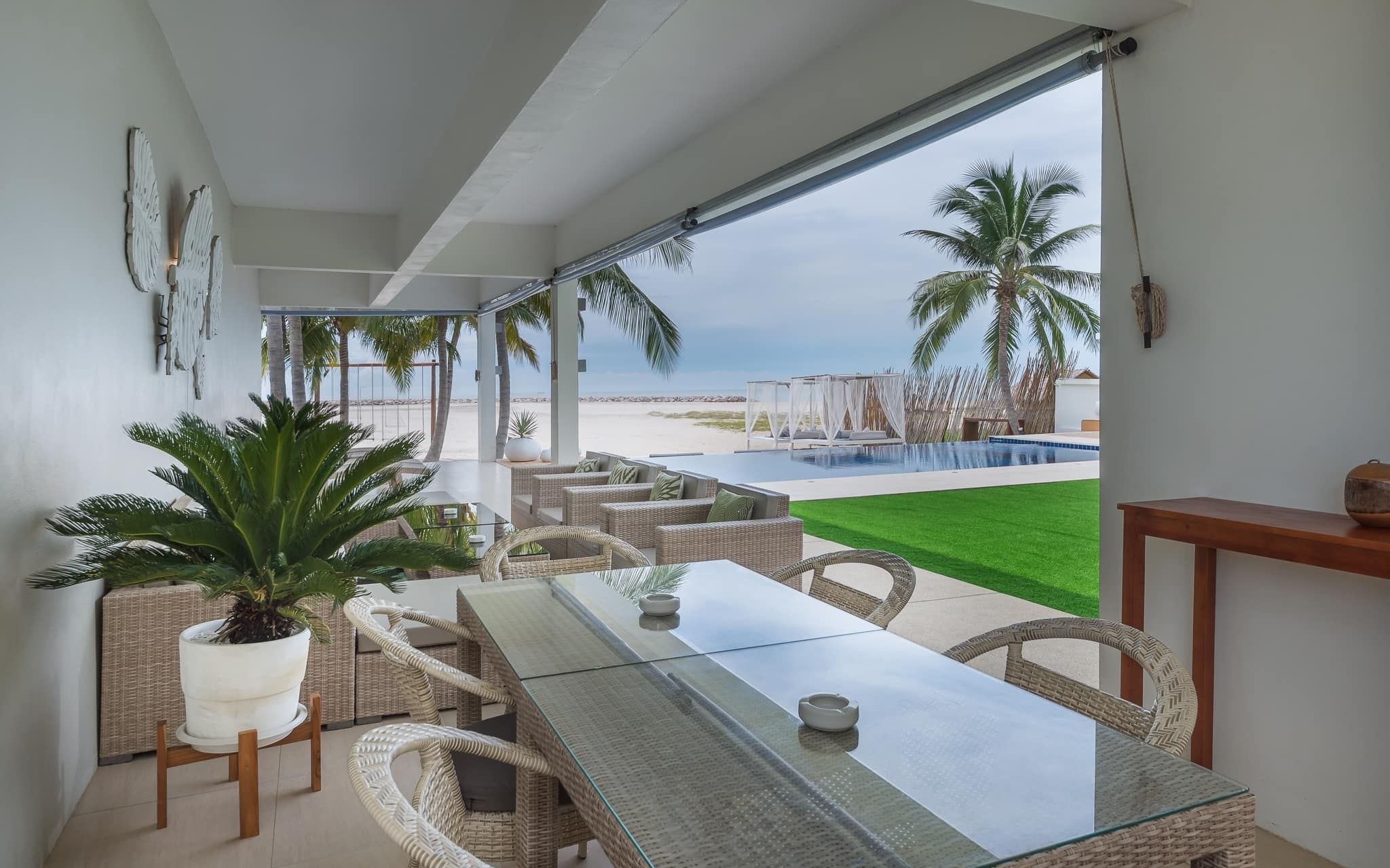 Vela VII Pool Villa, Cha-Am covered terrace with dining table overlooking pool and beach.