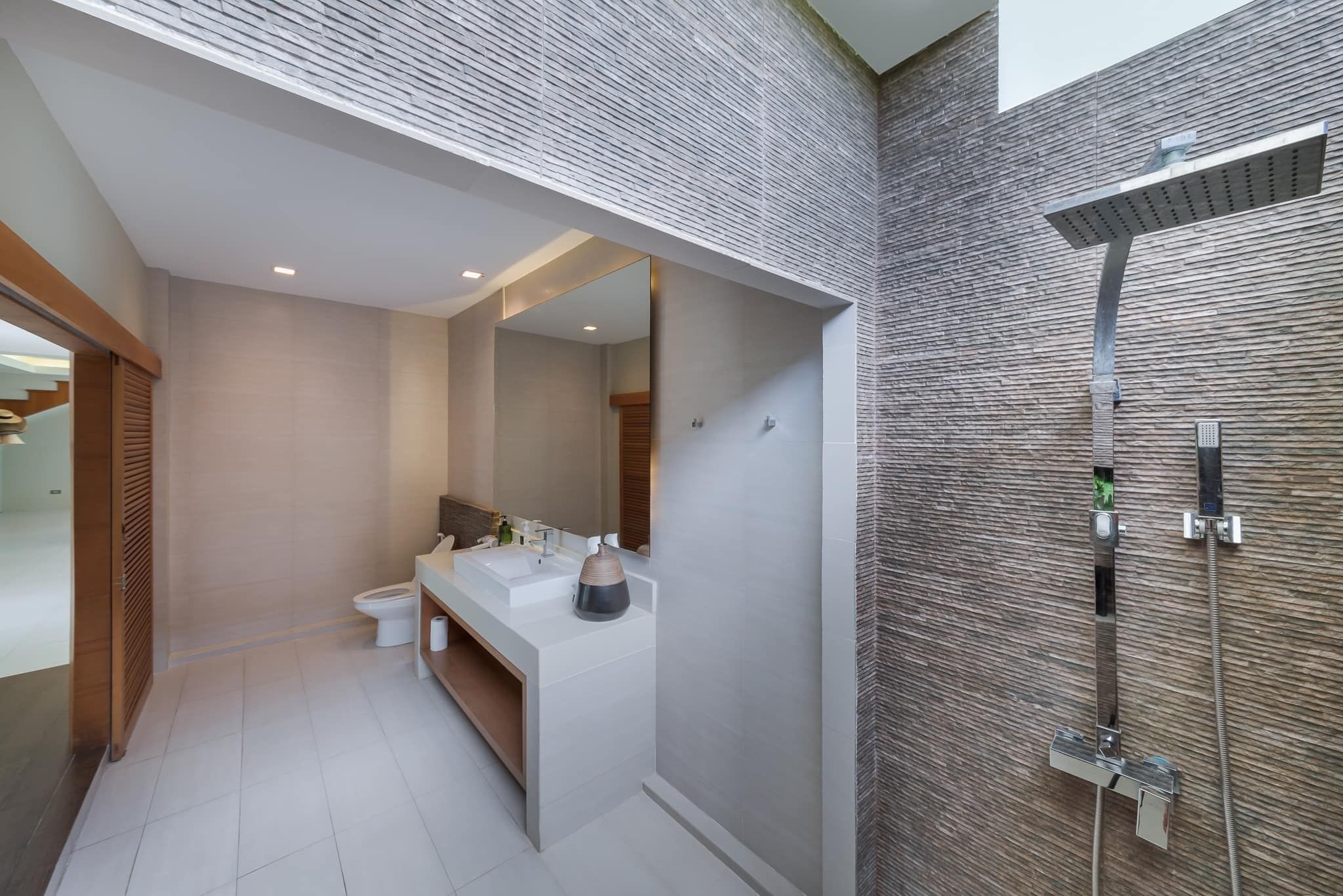 Modern bathroom with stone wall shower in Vela VII Pool Villa, Cha-Am, Thailand.