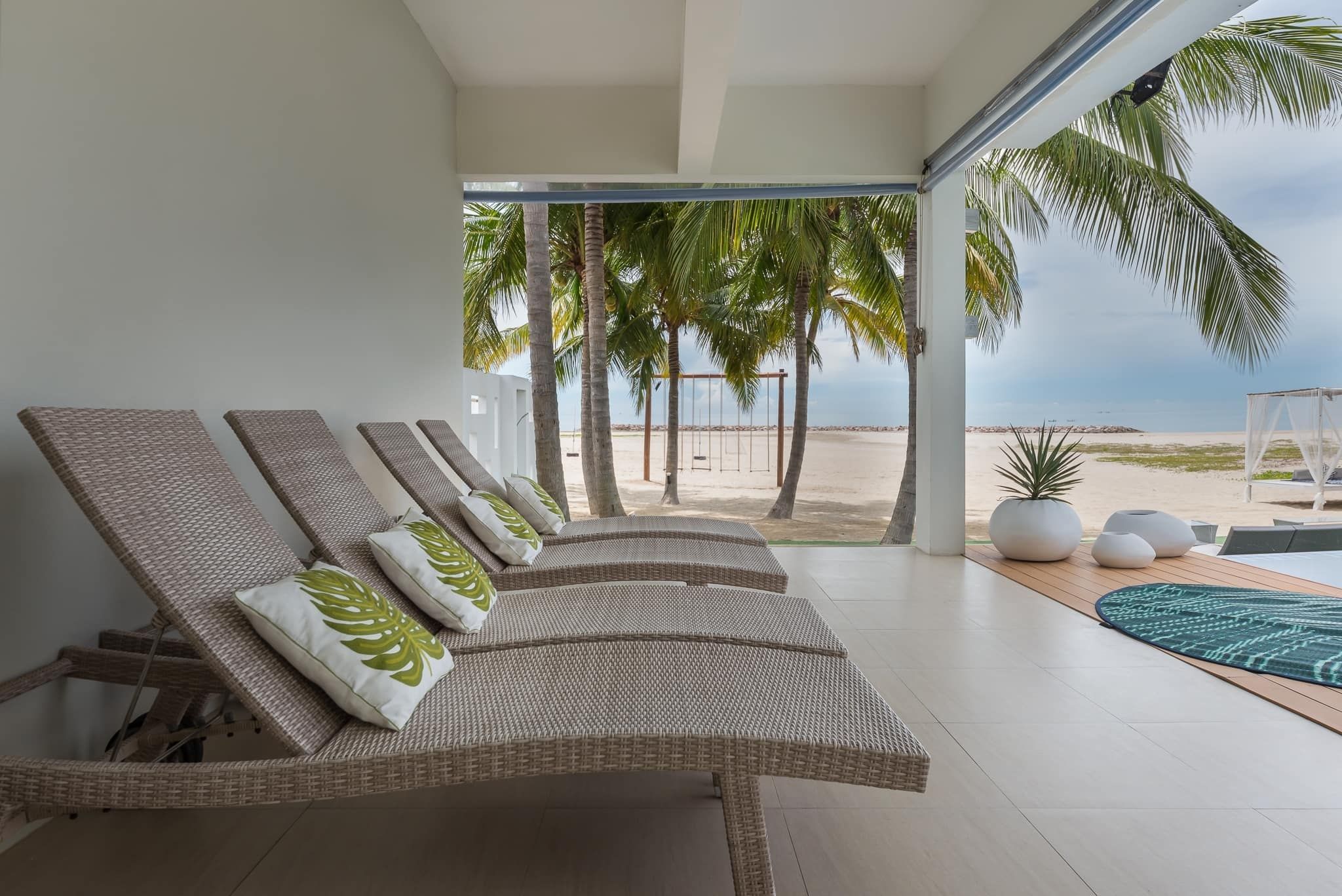 Relax on beachfront lounge chairs at Vela VII Pool Villa, Cha-Am. Enjoy stunning ocean views and direct beach access.