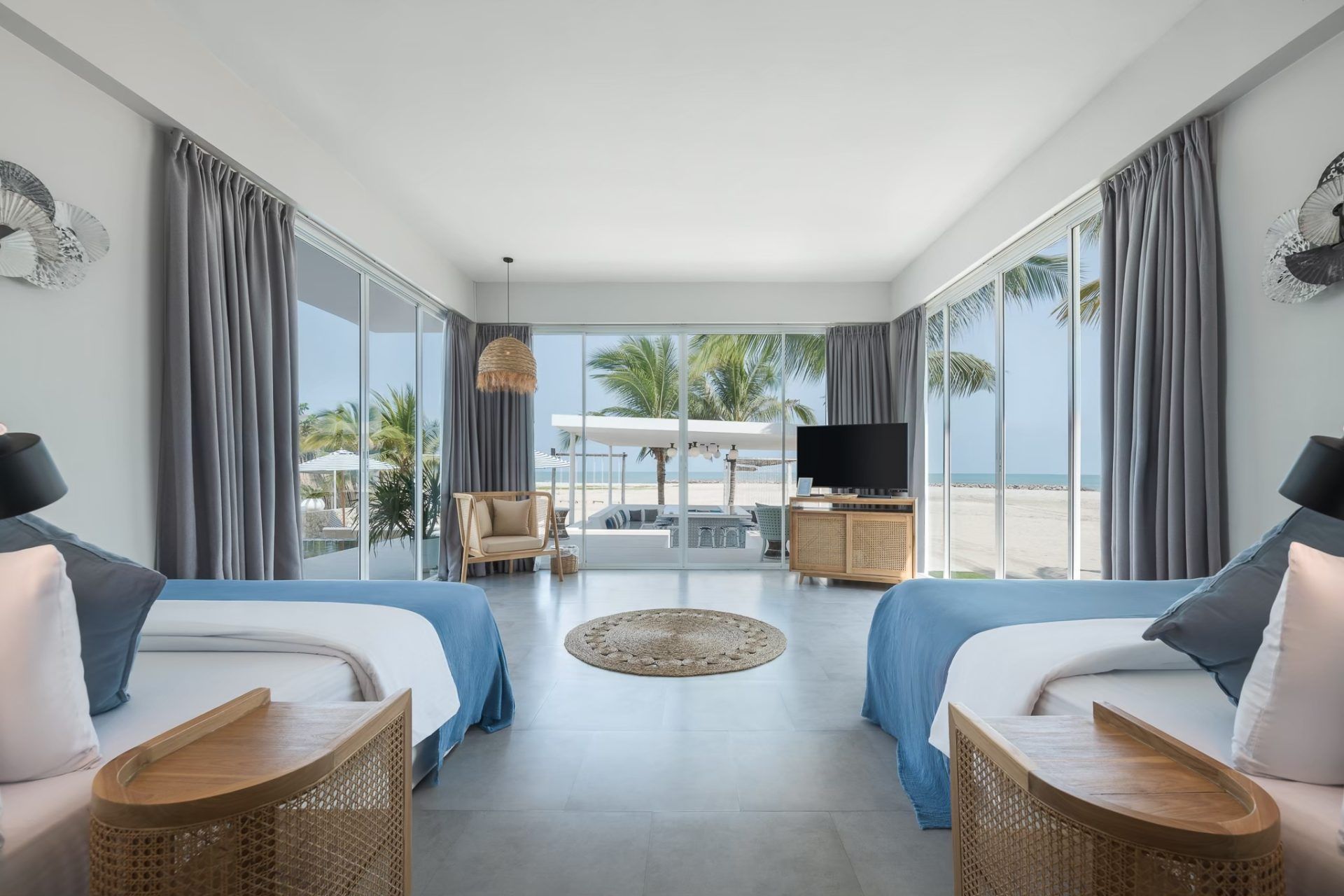 Twin beds in Vela VI Pool Villa, หาดปึกเตียน ชะอำ, with beachfront view through large windows. Wicker bedside tables.