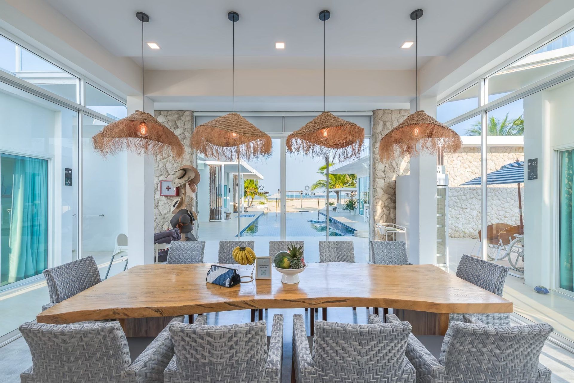 Dining area at Vela VI Pool Villa, Cha-am. Large live edge wood table with seating for ten, view of pool.