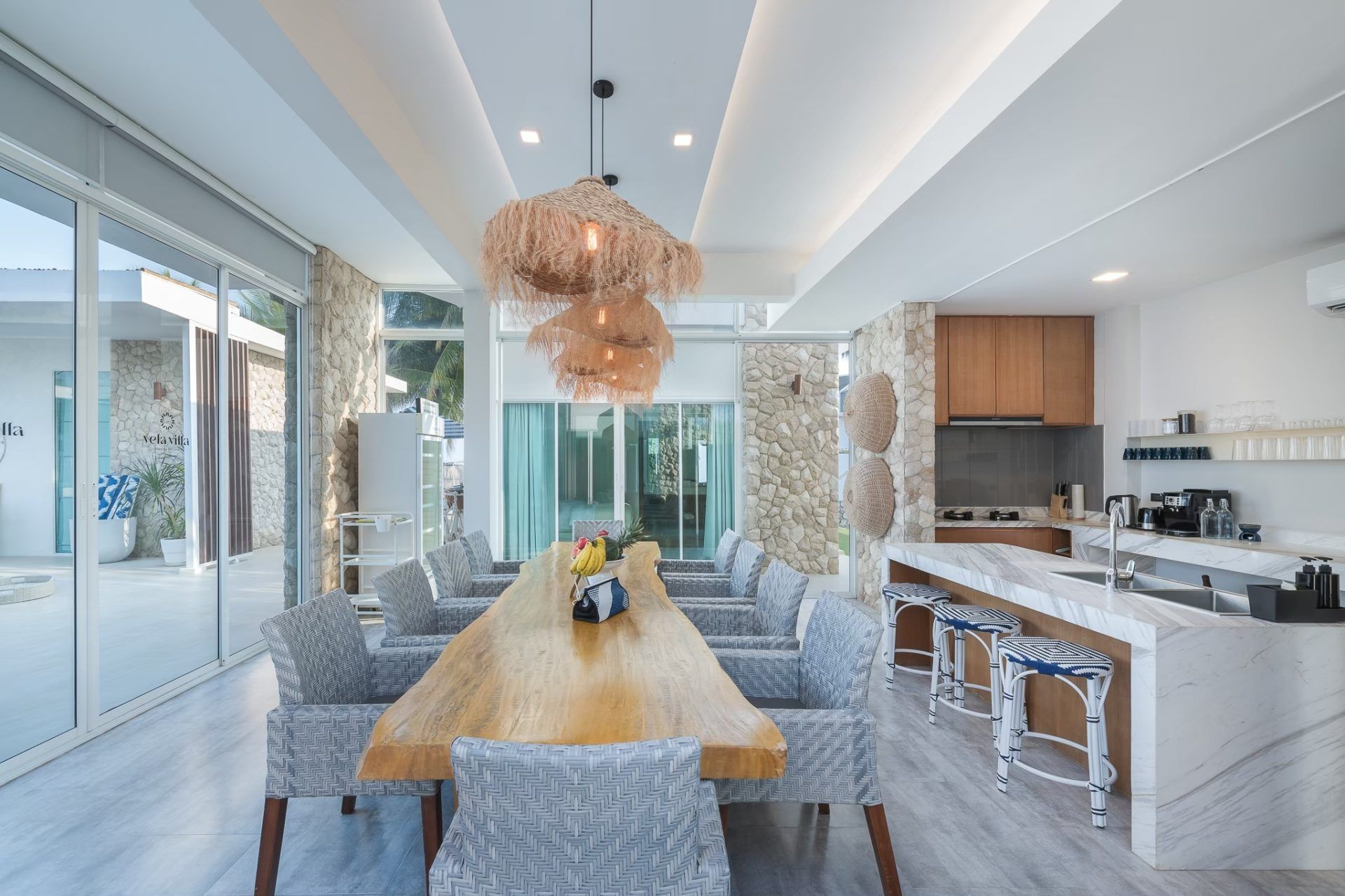 Dining area with long wood table at Vela VI Pool Villa, หาดปึกเตียน ชะอำ. Seating for ten guests.