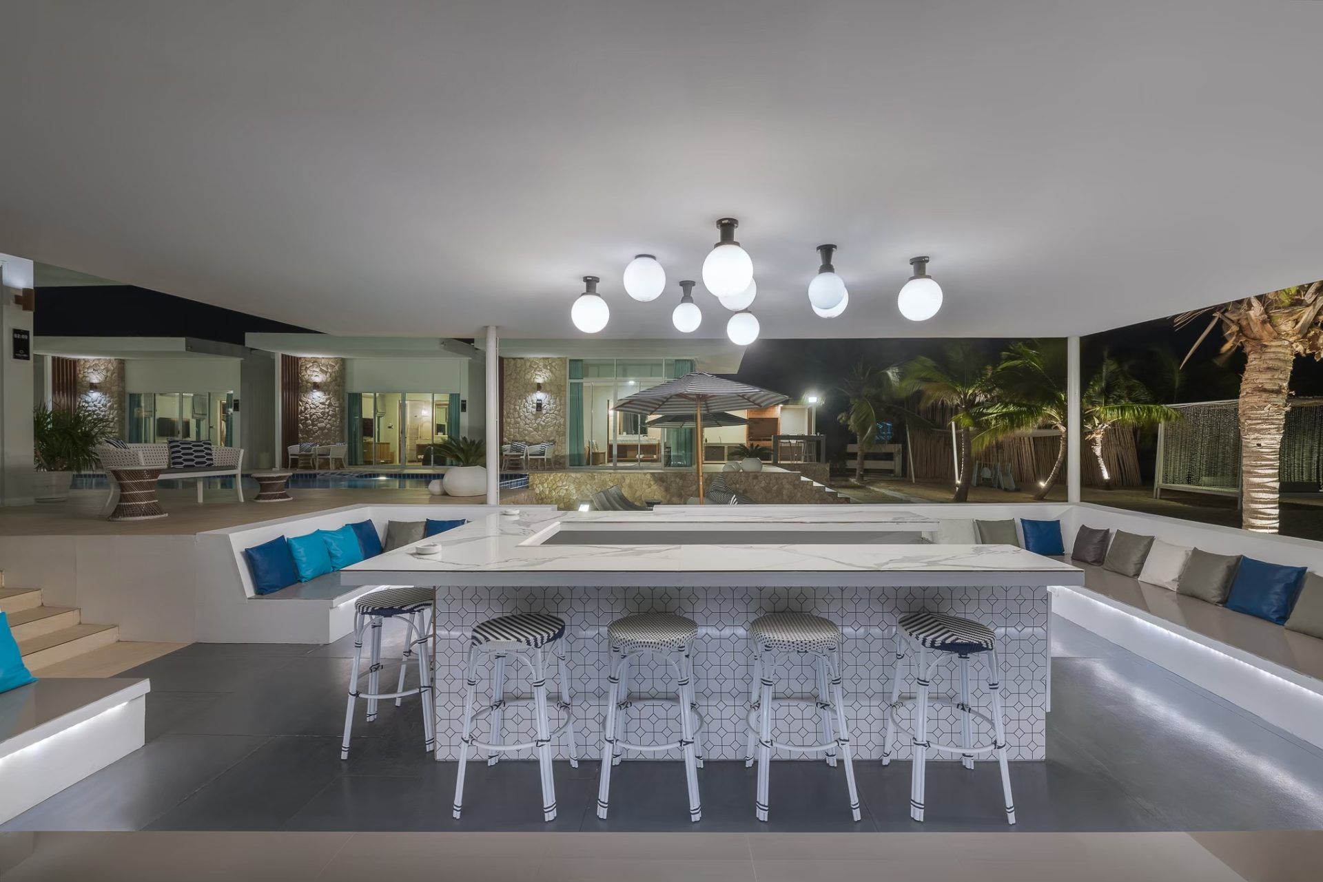 Outdoor bar seating at Vela VI pool villa, หาดปึกเตียน ชะอำ. White stools and cushions line the bar area overlooking the pool
