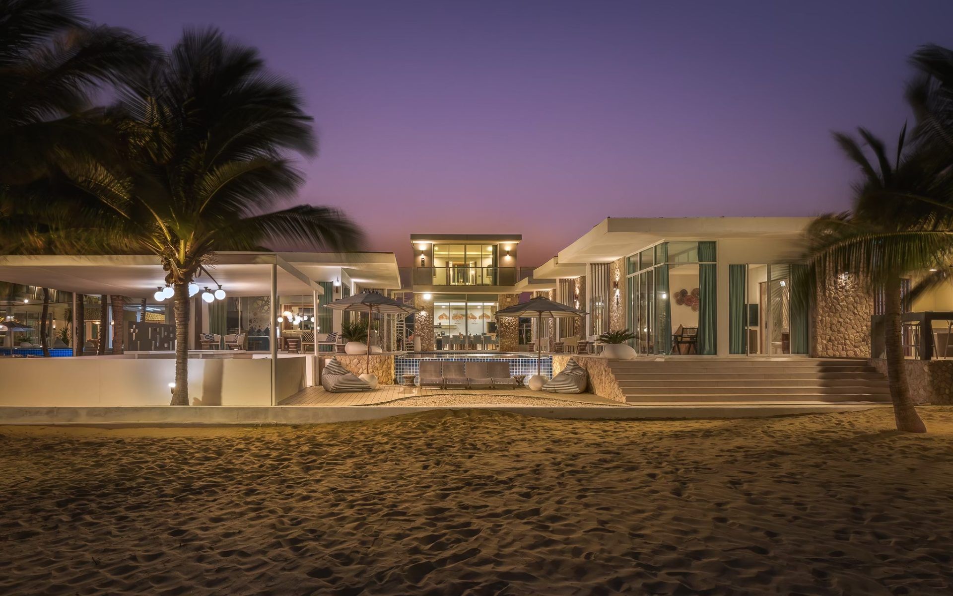 Vela VI Pool Villa beachfront view at dusk, หาดปึกเตียน ชะอำ. Modern villa with pool, palm trees, and beach access.