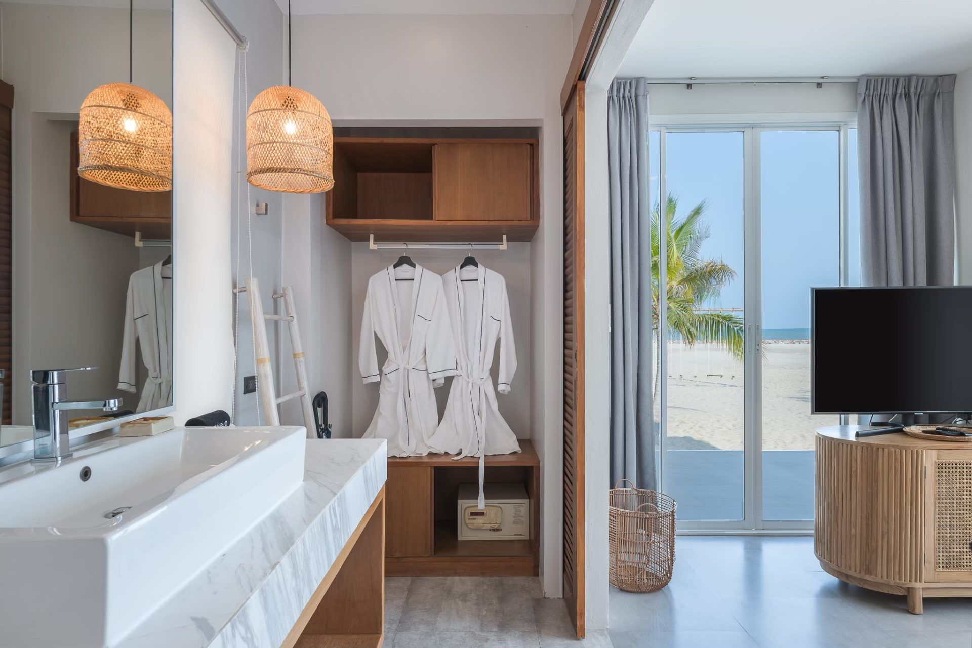 Ensuite bathroom with beach view at Vela VI Pool Villa, หาดปึกเตียน ชะอำ. Features robes, sink, and TV.