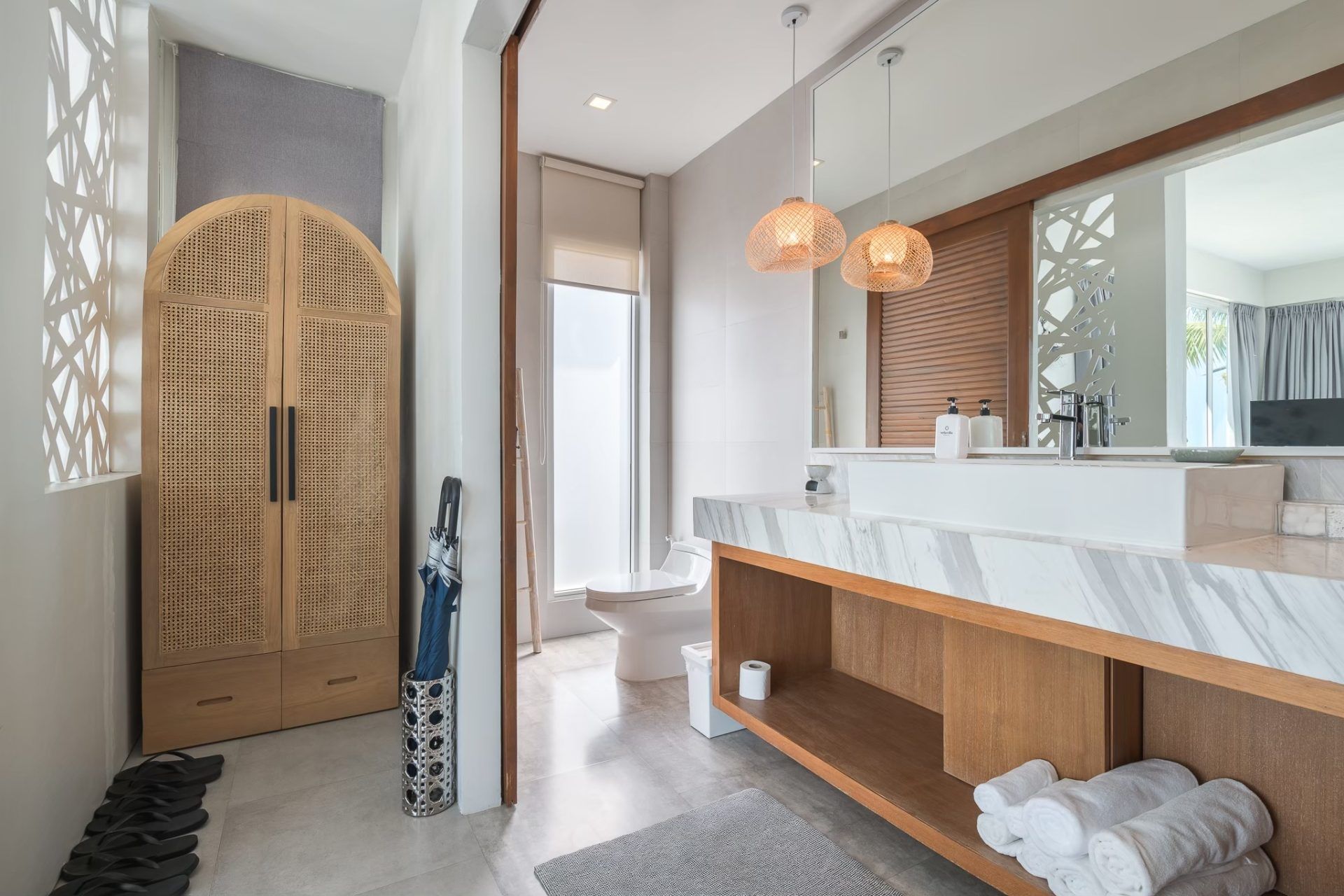 Bathroom with marble vanity and woven pendant lights at Vela VI pool villa, หาดปึกเตียน ชะอำ. Toilet and cabinet visible.