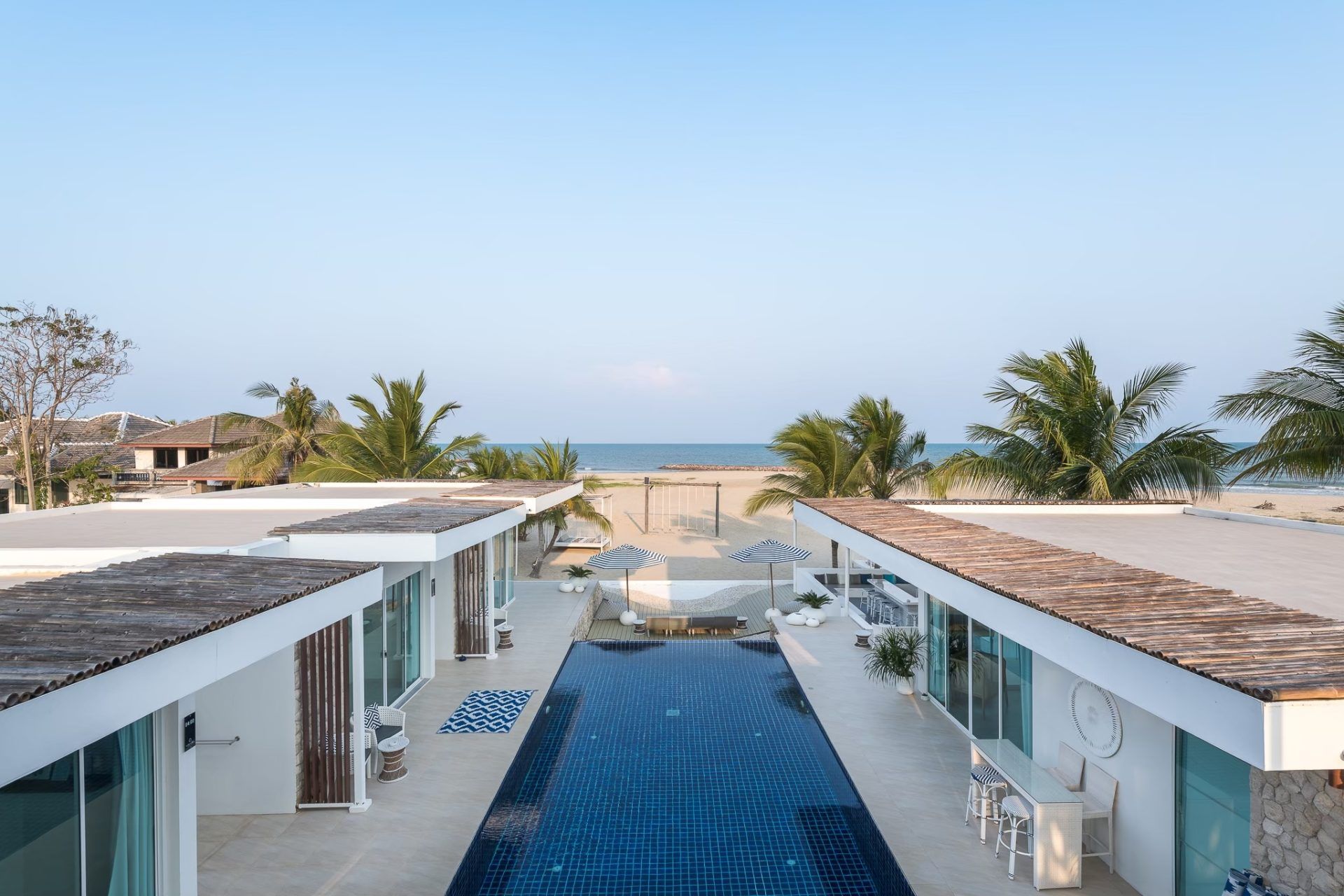 Aerial view of Vela VI pool villa in หาดปึกเตียน ชะอำ, Thailand. Blue tiled pool, beach access, and palm trees.