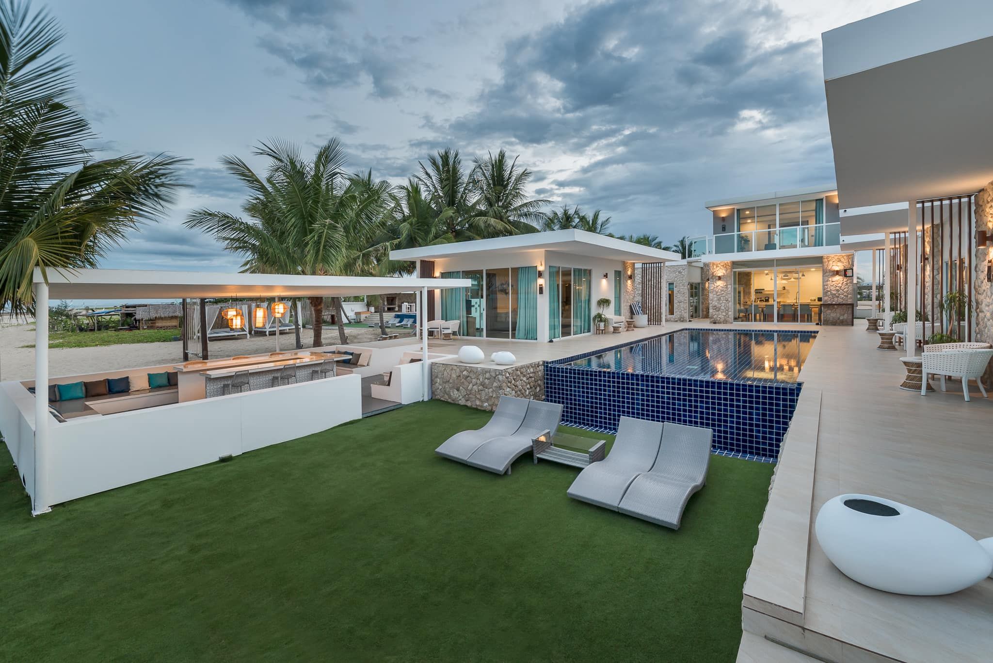 Vela VI Pool Villa poolside view in หาดปึกเตียน ชะอำ, Thailand. Lounge chairs on the lawn next to the pool.