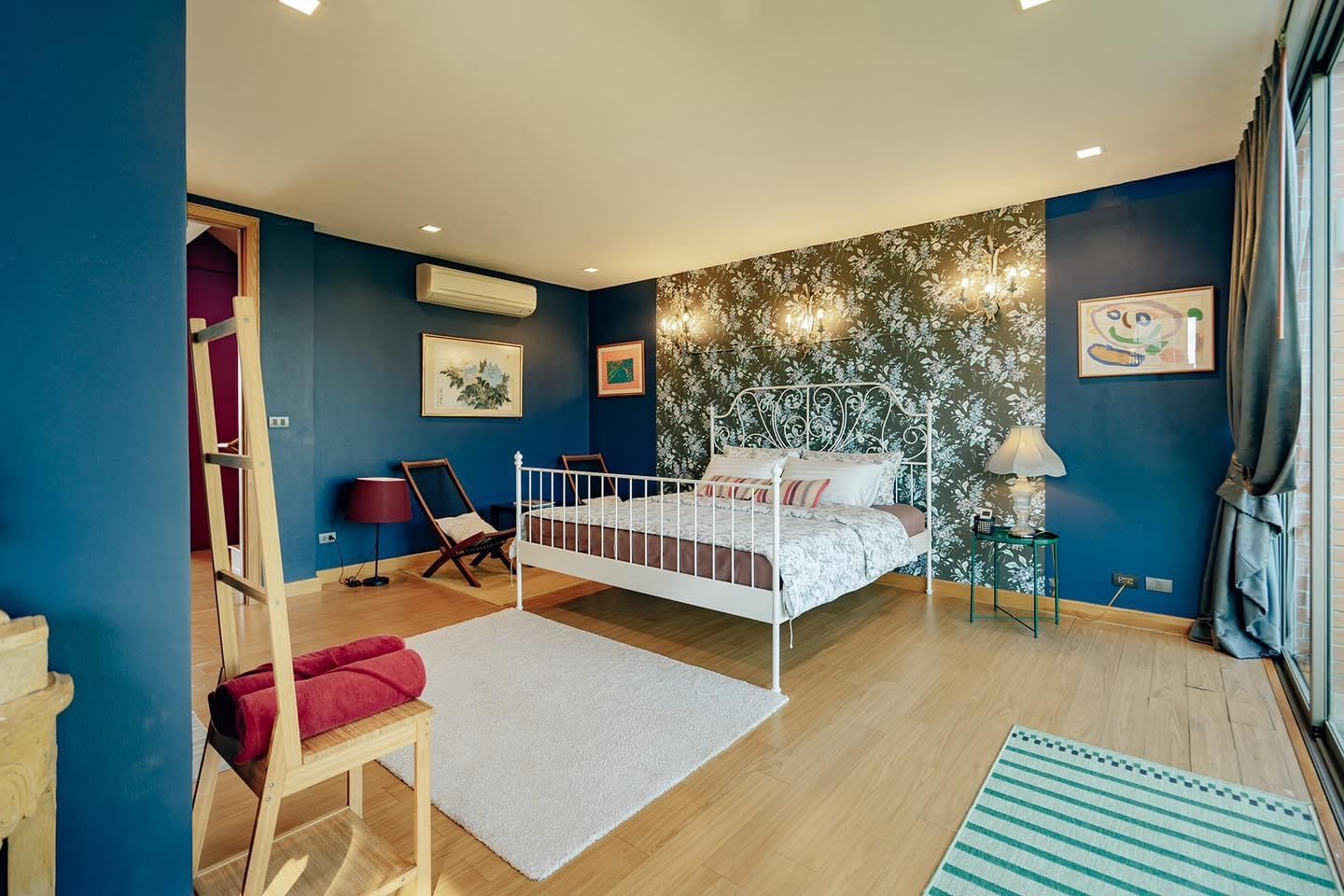 Bedroom at Pink Sand Beachfront Villa, บางละมุง พัทยาเหนือ. White metal bed frame, floral wallpaper, and blue walls.
