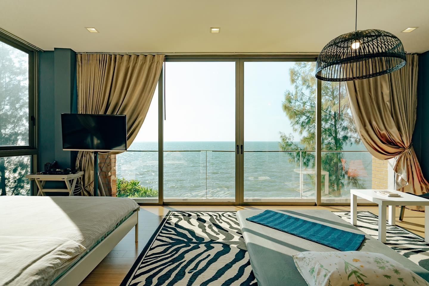 Pink Sand Beachfront Villa bedroom in บางละมุง with ocean view, zebra rug, and large windows.