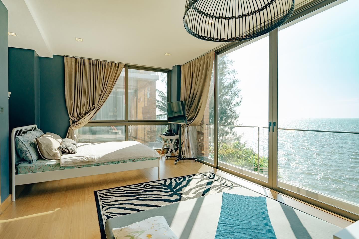 Bright bedroom with ocean view at Pink Sand Beachfront Villa, บางละมุง พัทยาเหนือ. Features a zebra rug and large windows.