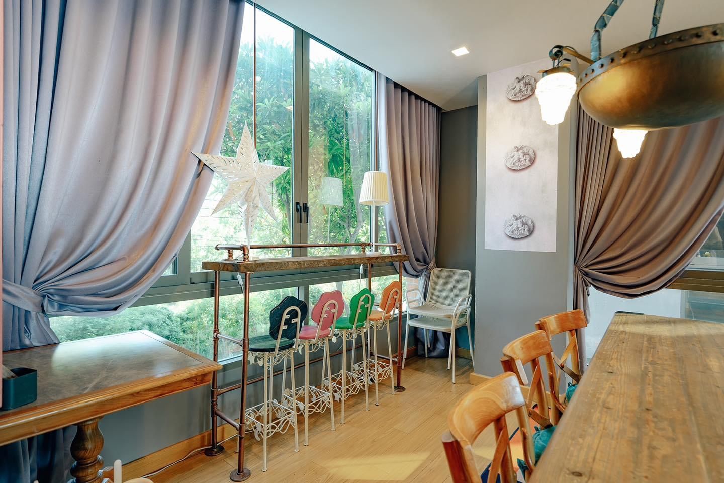Dining area with colorful bar stools at Pink Sand Beachfront Villa, Bang Lamung, North Pattaya. Unique seating by the window.