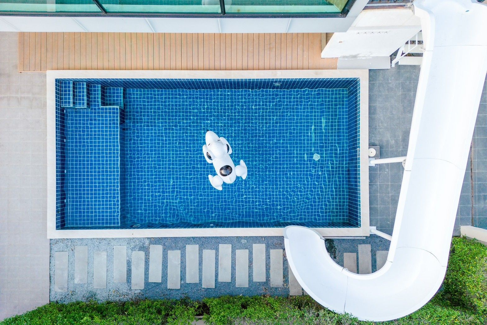 Aerial view of Pool Lay A III Pool Villa's blue-tiled pool with slide and Snoopy floatie, นาจอมเทียน-ห้วยใหญ่ พัทยาใต้.