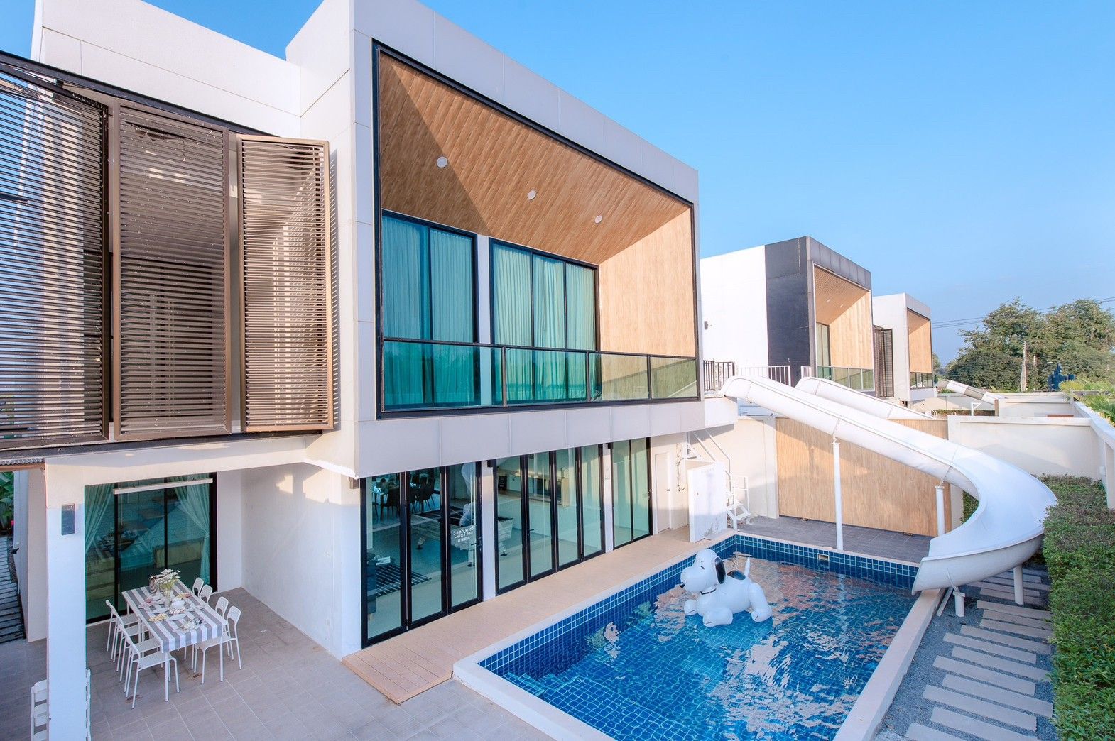 Pool Lay A III Pool Villa in Pattaya with water slide and inflatable dog. Modern architecture and outdoor dining.