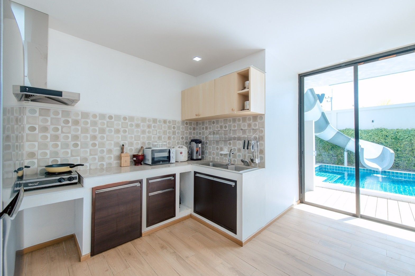 Modern kitchen with pool view at Pool Lay AII Pool Villa, Na Jomtien. See the waterslide from the kitchen window!