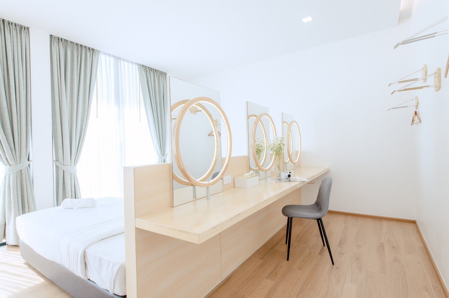 Bright bedroom at Pool Lay AII Pool Villa, Na Jomtien. Features a vanity with round mirrors and a modern chair.