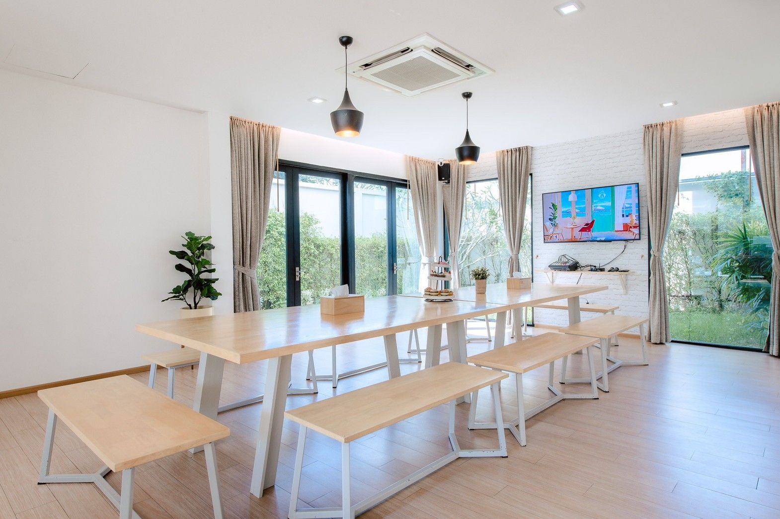 Bright dining area with long wooden table and benches at Pool Lay AII Pool Villa, Na Jomtien, Pattaya.