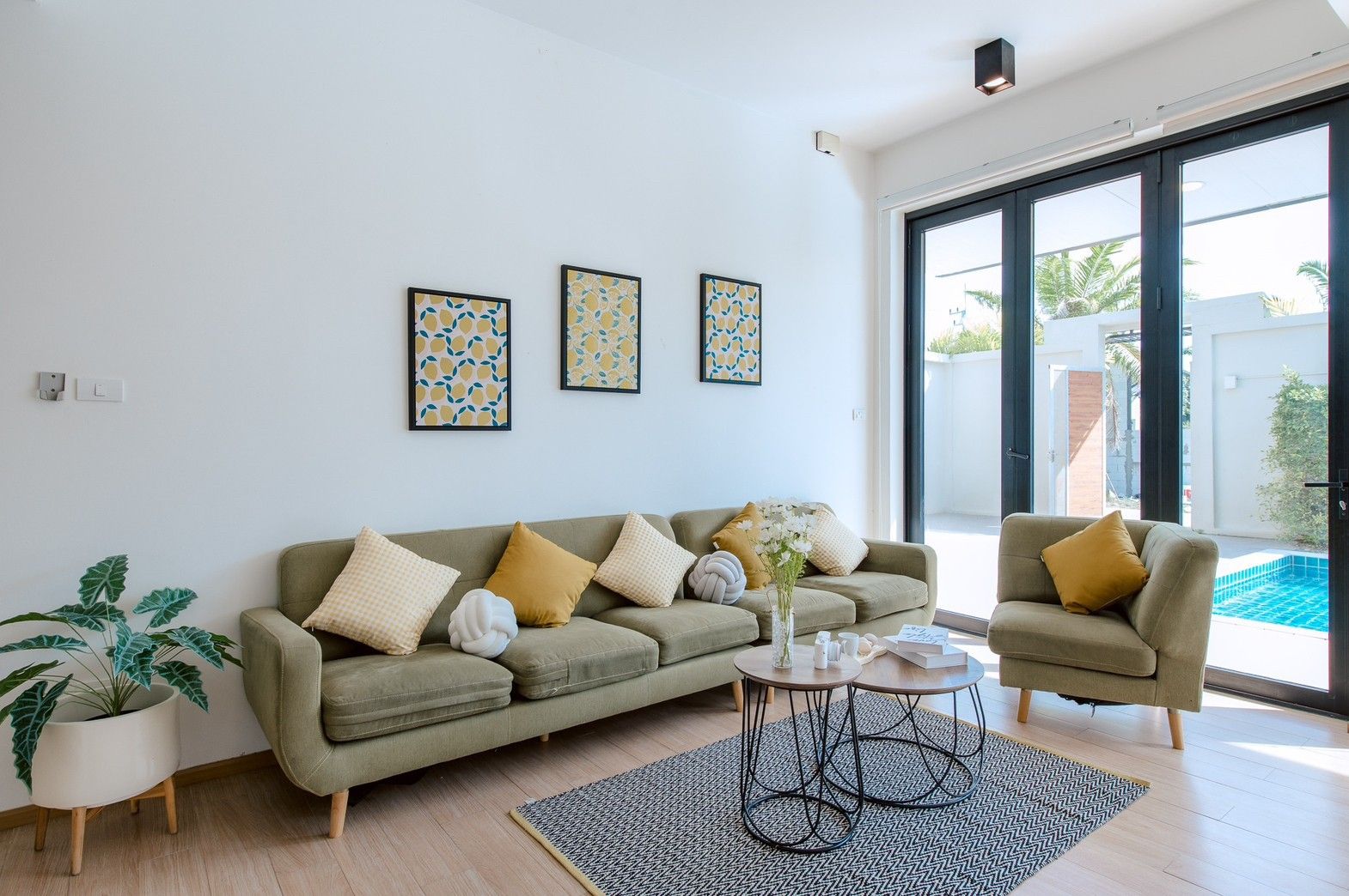 Stylish living room at Pool Lay AII Pool Villa, Na Jomtien, Pattaya. Olive green sofa, modern decor, and pool view.