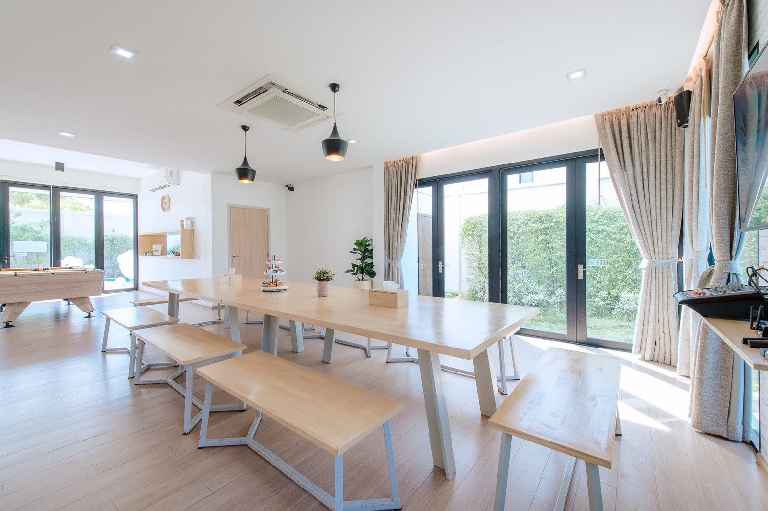 Bright dining area with large table and benches at Pool Lay AII Pool Villa, Na Jomtien, Pattaya, Thailand.