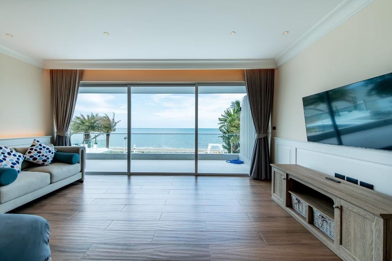 Living room with ocean view at Private Heaven VI Pool Villa, Cha-Am. Sofa, TV, and sliding glass doors to balcony.