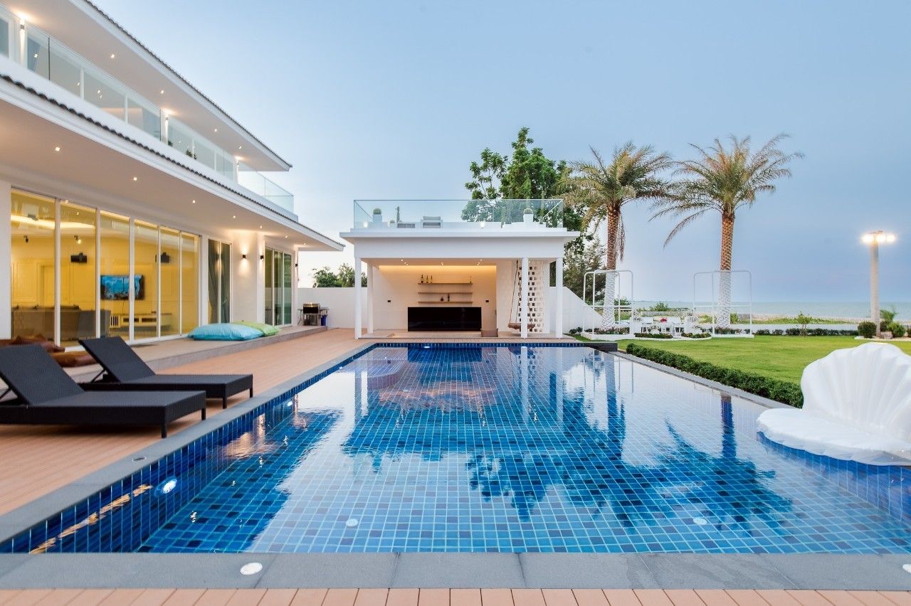 Stunning blue tiled pool at Private Heaven VI Pool Villa, Cha-Am. Loungers, bar, and ocean views.