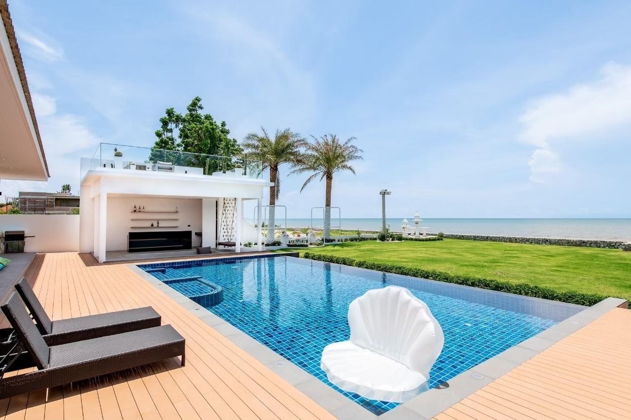 Private Heaven VI pool villa in Cha-Am. View of the pool with a shell-shaped float, pool bar, and ocean view.
