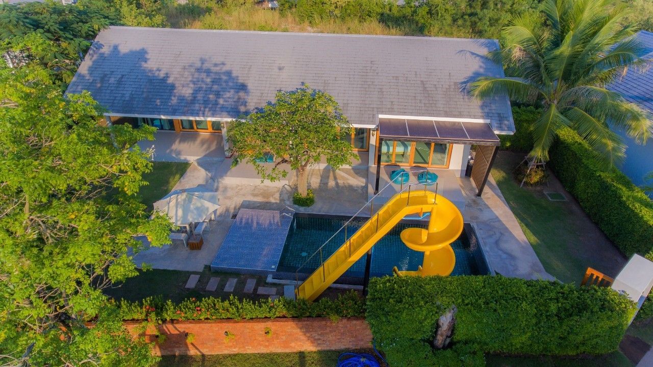 Aerial view of Proud I Pool Villa Hua Hin with swimming pool and yellow slide.