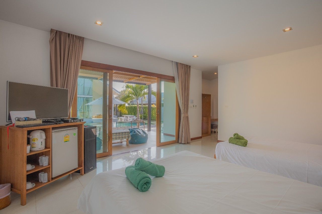 Bright bedroom with pool view at Proud II Pool Villa, Hua Hin. Features twin beds, TV, and sliding glass doors to the pool.