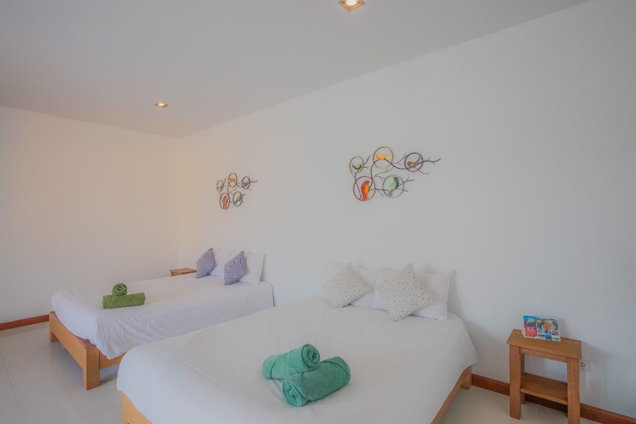 Bright bedroom with twin beds and colorful wall decor at Proud II Pool Villa, Hua Hin, Thailand.