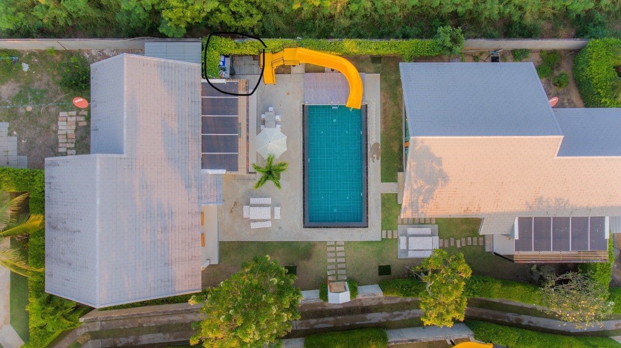 Aerial view of Proud II Pool Villa in Hua Hin, featuring a pool with slide, solar panels, and outdoor seating.