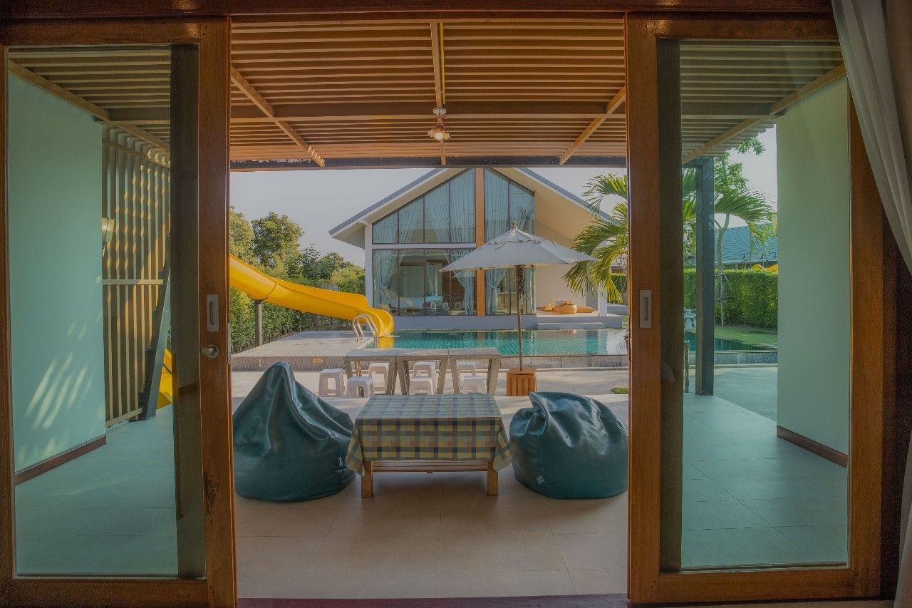 View of the pool and slide from the patio at Proud II Pool Villa, Hua Hin. Beanbag chairs and outdoor dining.