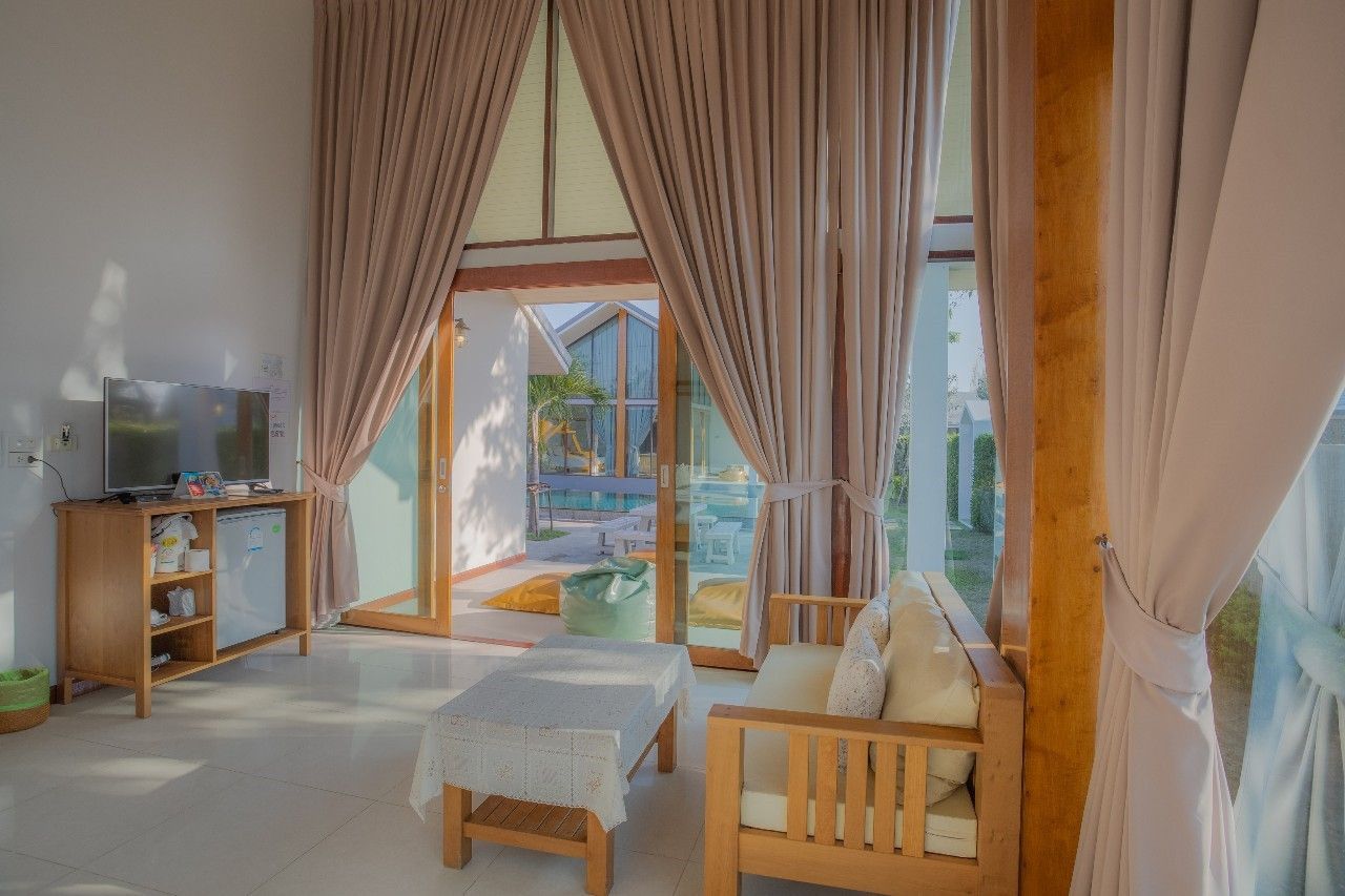 Bright living room with pool view at Proud II Pool Villa, Hua Hin. Features sofa, TV, and natural light.