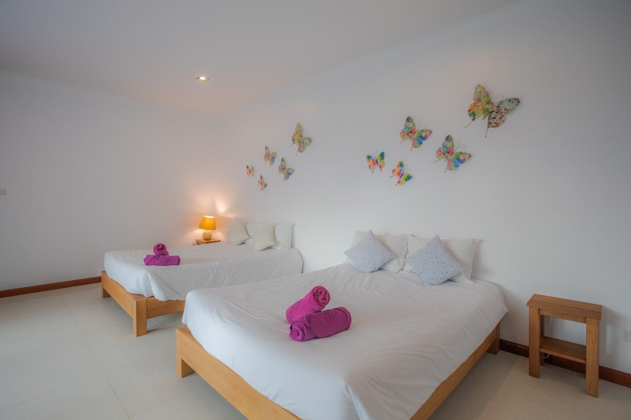 Bedroom with twin beds and butterfly wall art at Proud II Pool Villa, Hua Hin, Thailand.