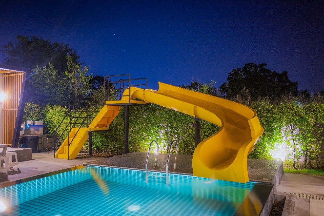 Night view of the pool with a yellow slide at Proud II Pool Villa, Hua Hin, Thailand.