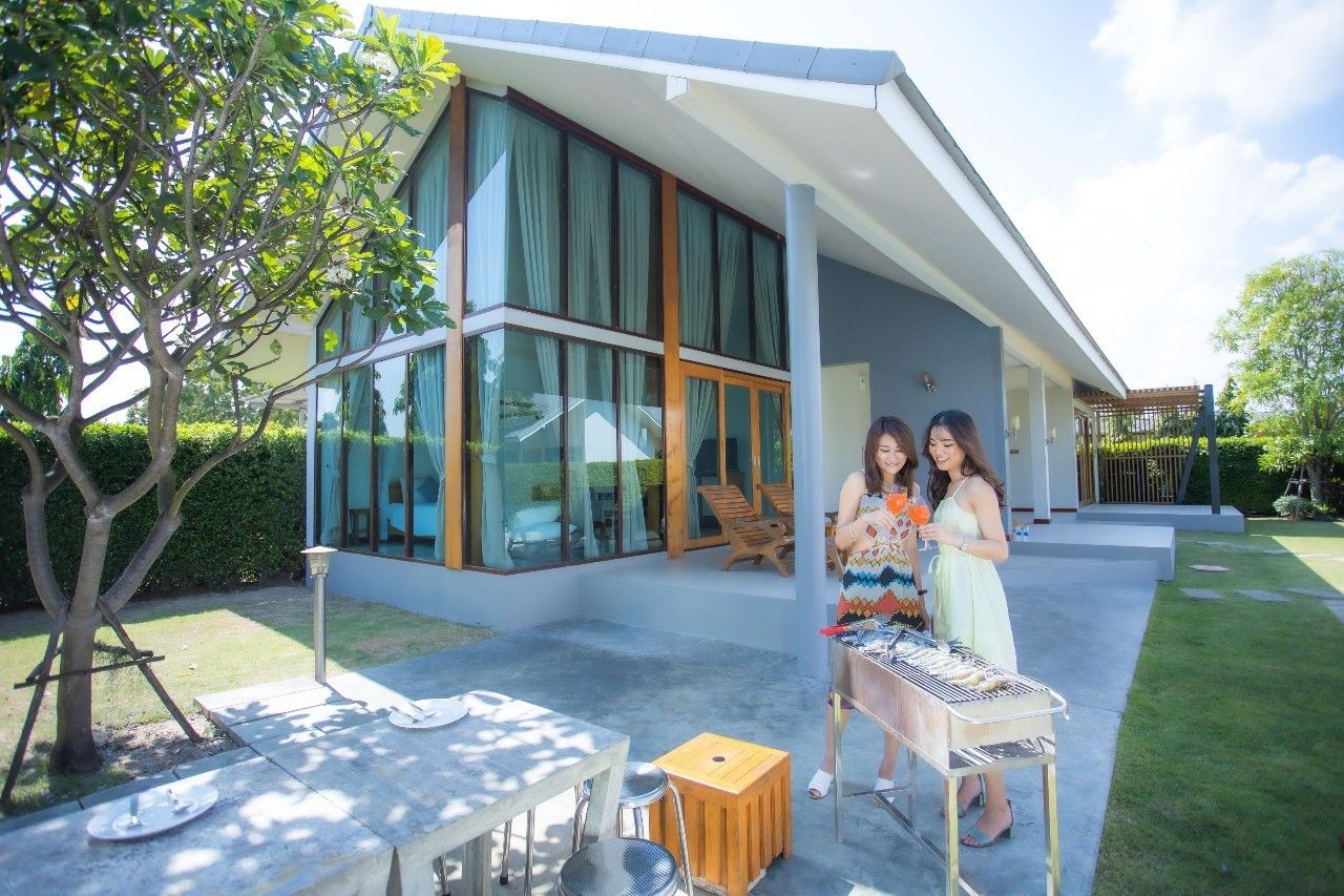Guests enjoy a BBQ at Proud III Pool Villa, Hua Hin. Outdoor dining and grilling area.
