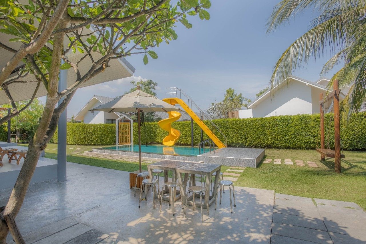 Outdoor dining table and pool with slide at Proud III Pool Villa, Hua Hin. Perfect for family fun in Thailand.