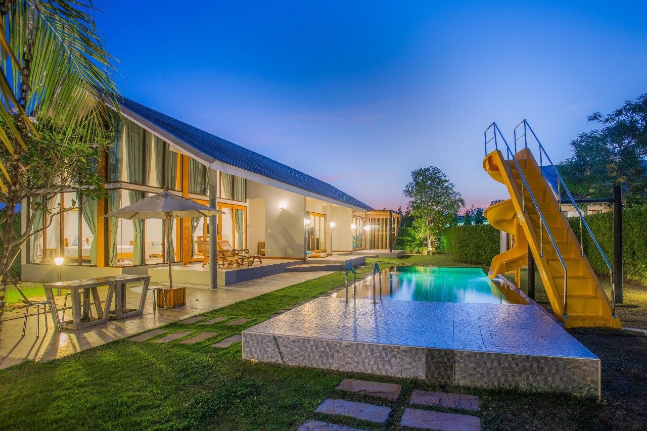 Evening view of Proud III Pool Villa in Hua Hin with a swimming pool and yellow water slide.