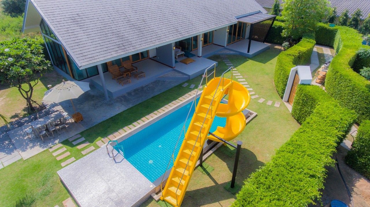 Aerial view of Proud III Pool Villa in Hua Hin with a pool and yellow water slide for family fun.
