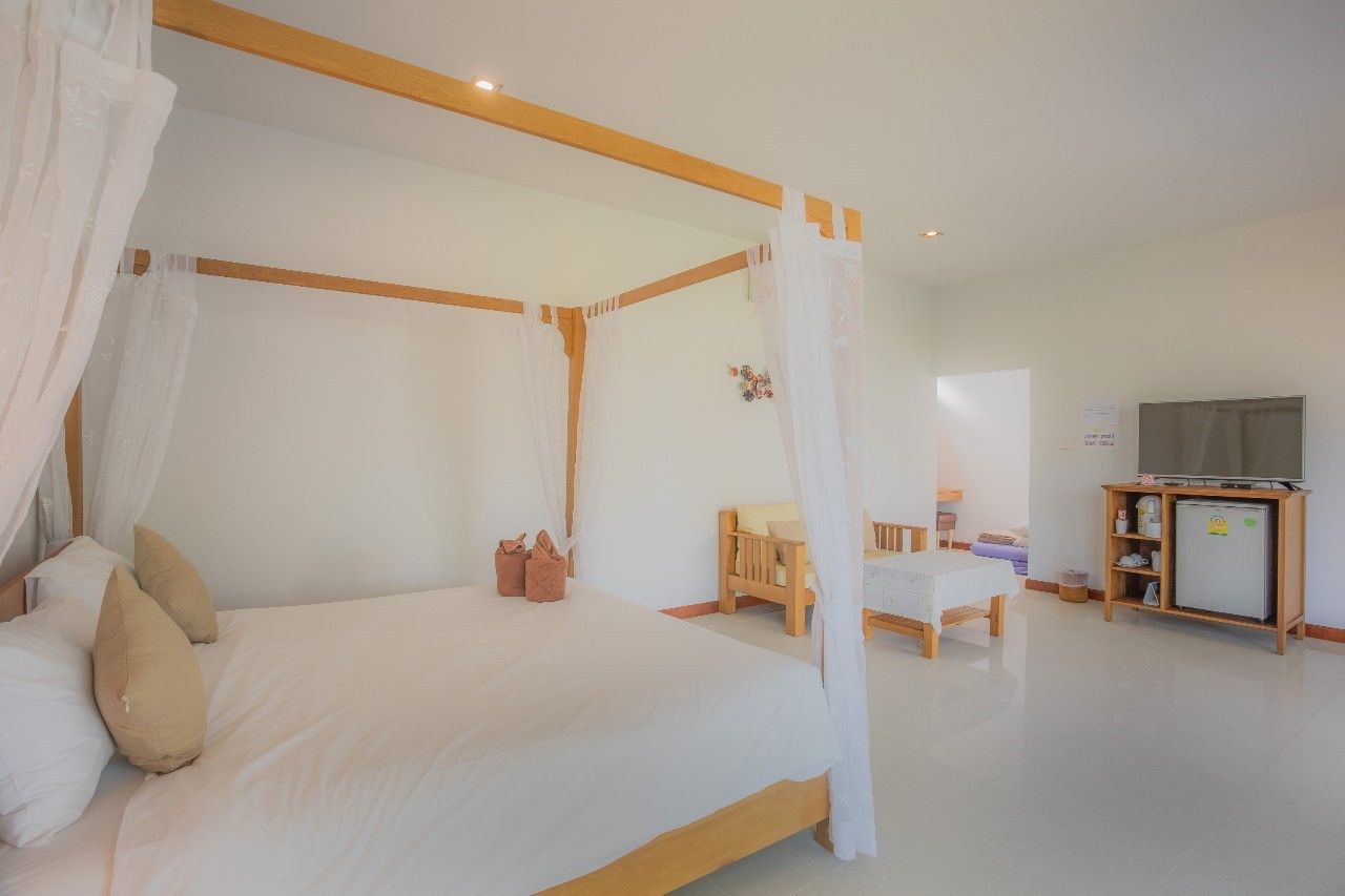 Bedroom with four-poster bed at Proud IV Pool Villa, Hua Hin. Light and airy room with TV and seating area.