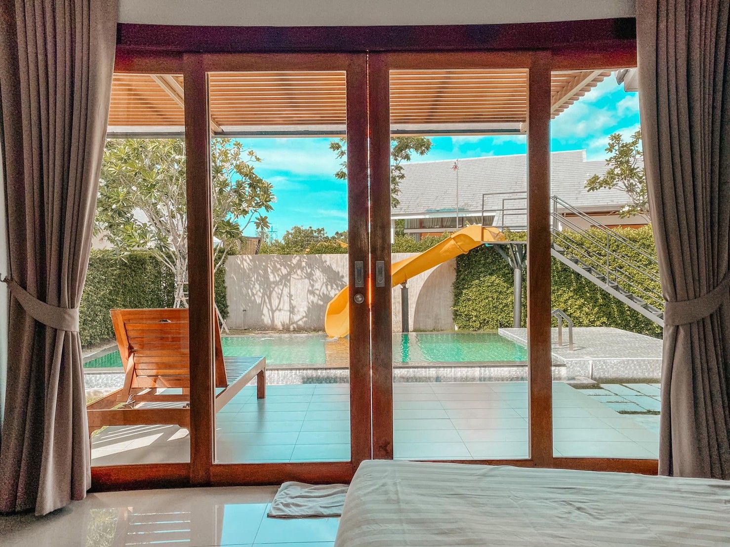View of the pool and waterslide from the bedroom at Proud IV Pool Villa, Hua Hin, Thailand.