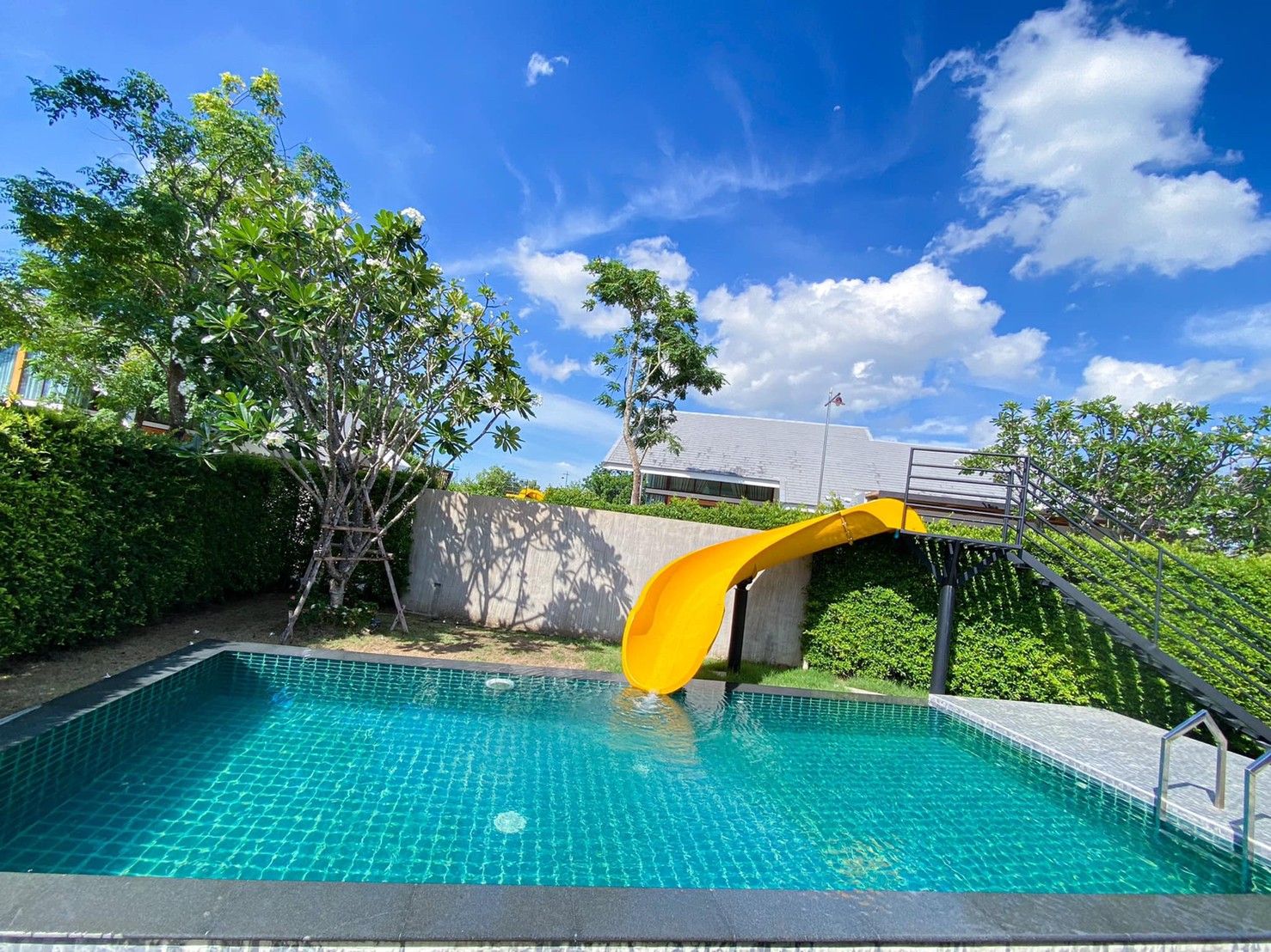 Bright yellow water slide leading into the pool at Proud IV Pool Villa, Hua Hin, Thailand.