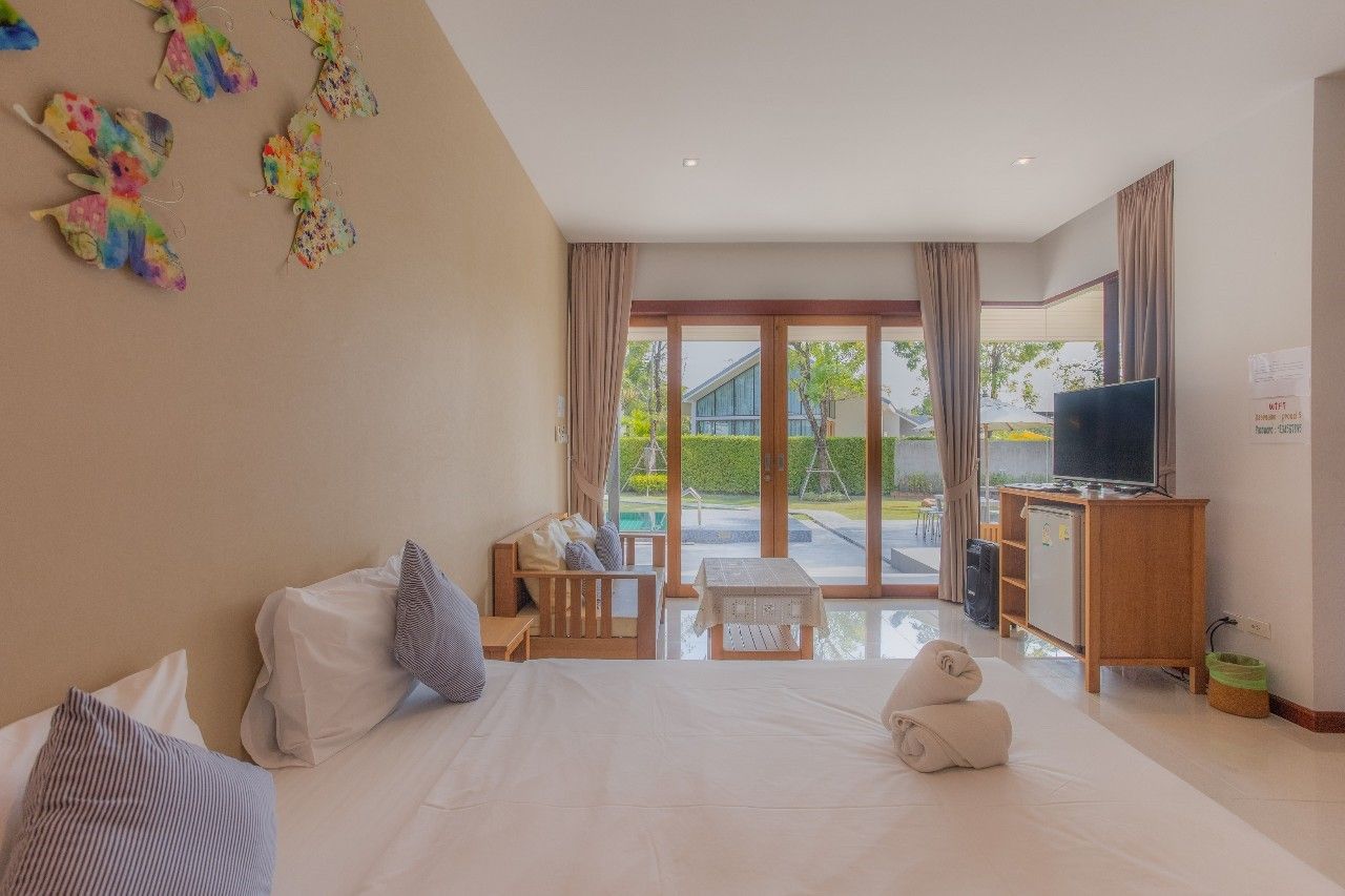 Bright bedroom with pool view at Proud V Pool Villa, Hua Hin. Features a comfortable bed and outdoor access.