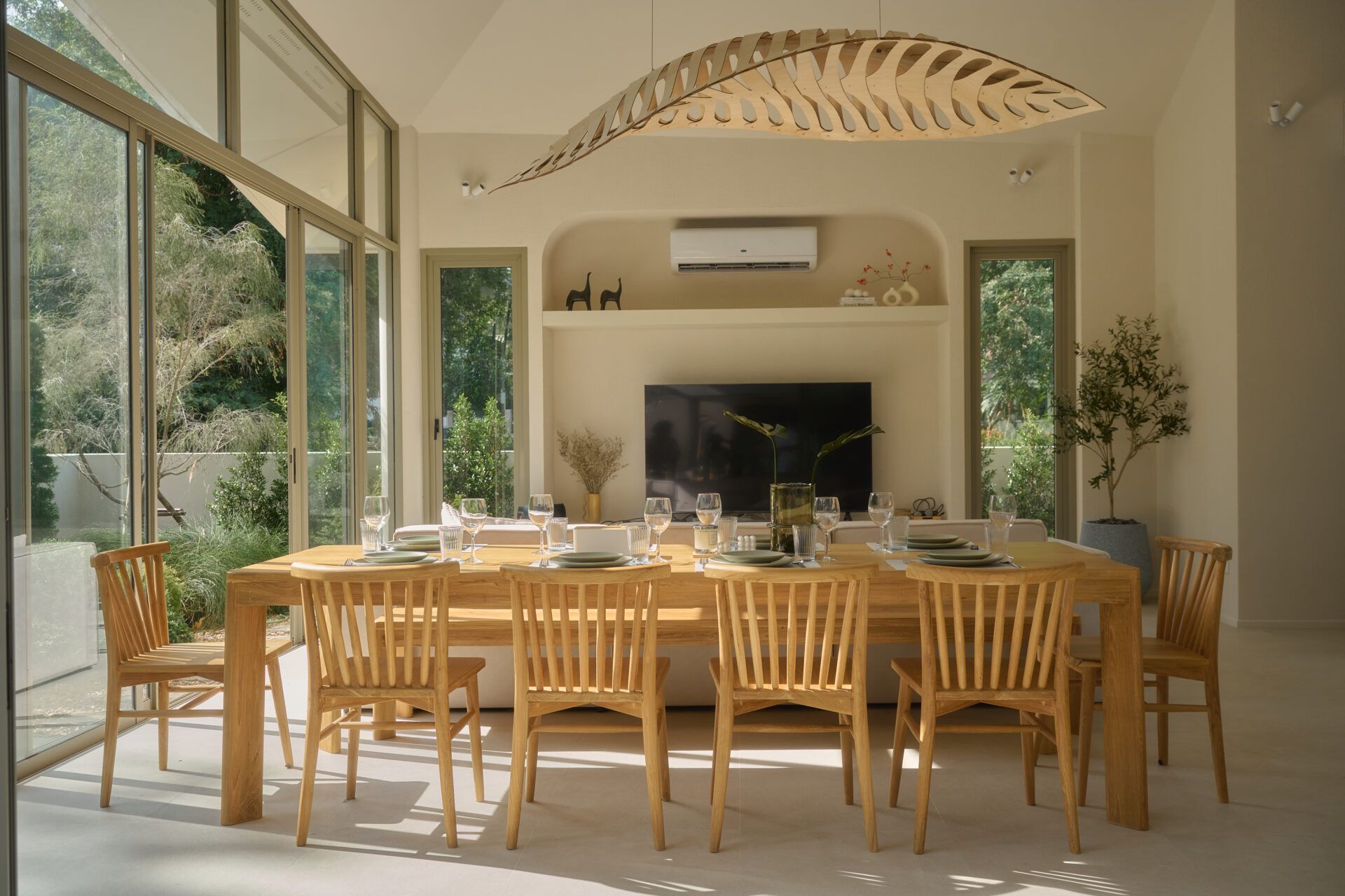 Roove V Pool Villa near Khaoyai National Park dining area with wooden table set for a meal. Large windows offer garden views.