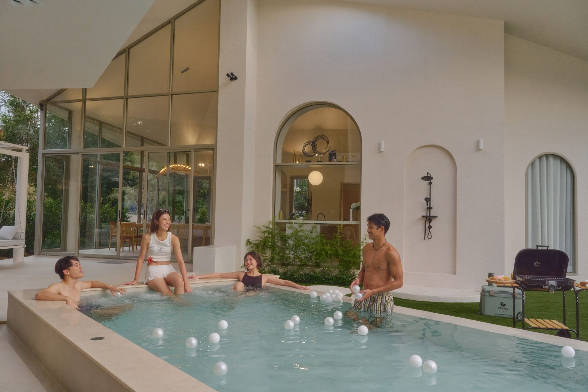 People enjoy the pool with balls at Roove V Pool Villa near Khaoyai National Park. Outdoor shower and BBQ visible.